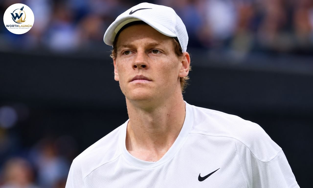 Jannik Sinner in a white tennis outfit and cap during a professional tennis match.