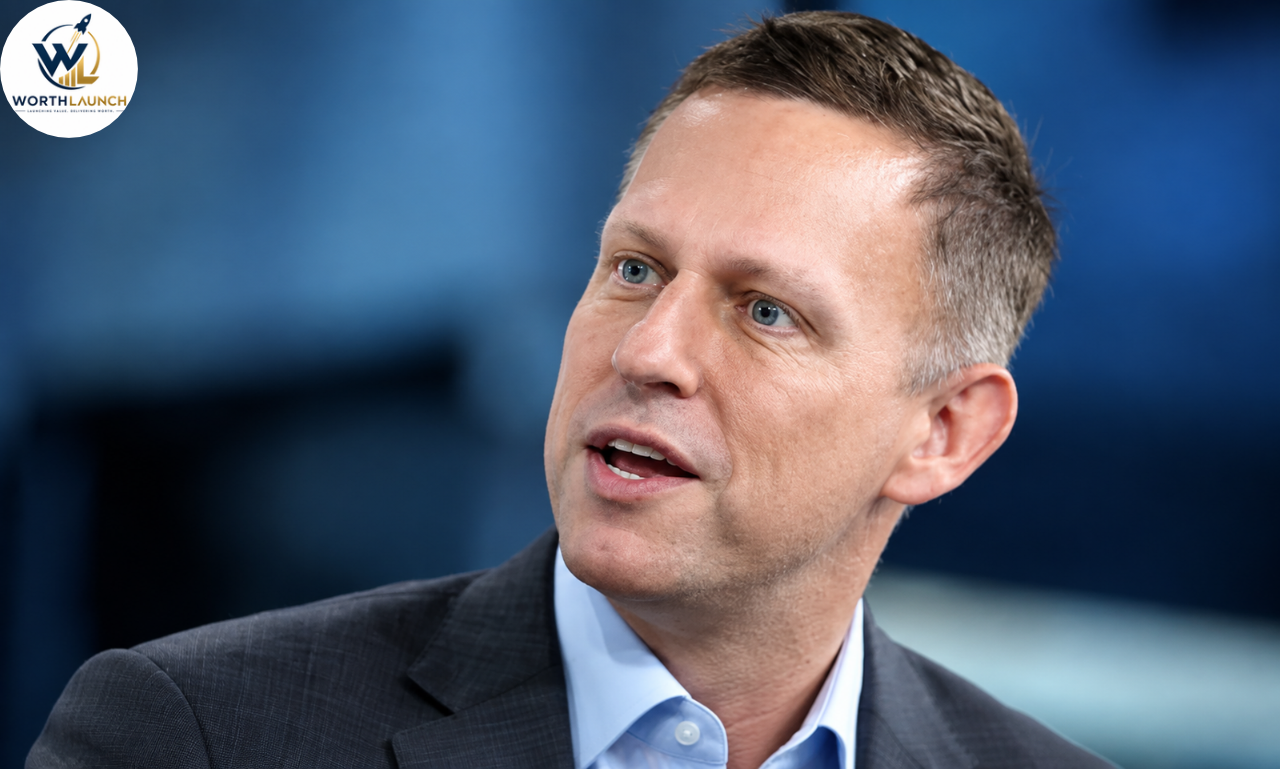 Matt Danzeisen in a dark suit and light blue shirt speaking during a professional interview against a blue background.