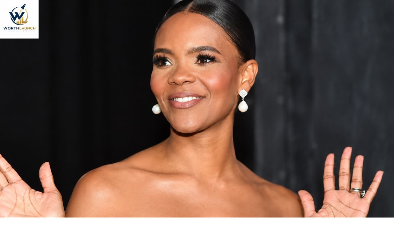 Smiling woman in a black strapless dress posing with raised hands at a red-carpet event.