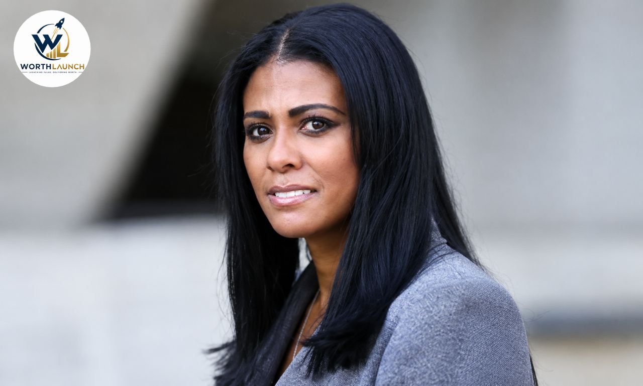 Tyna Karageorge posing for a portrait in a gray blazer with long black hair.