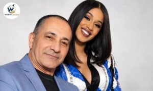 Carlos Alman posing with Cardi B in a blue outfit against a clean studio background.