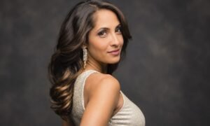 Christel Khalil in a champagne-colored outfit with long dark wavy hair and elegant earrings.