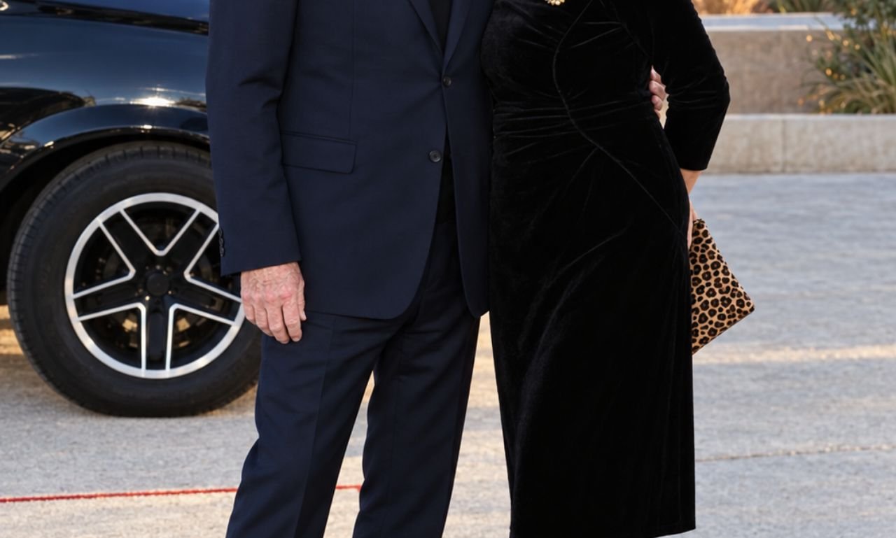 "Jonathan Banks and Gennera Gonzalez Cebian posing together outdoors in elegant black outfits, with a car and scenic desert mountains in the background."