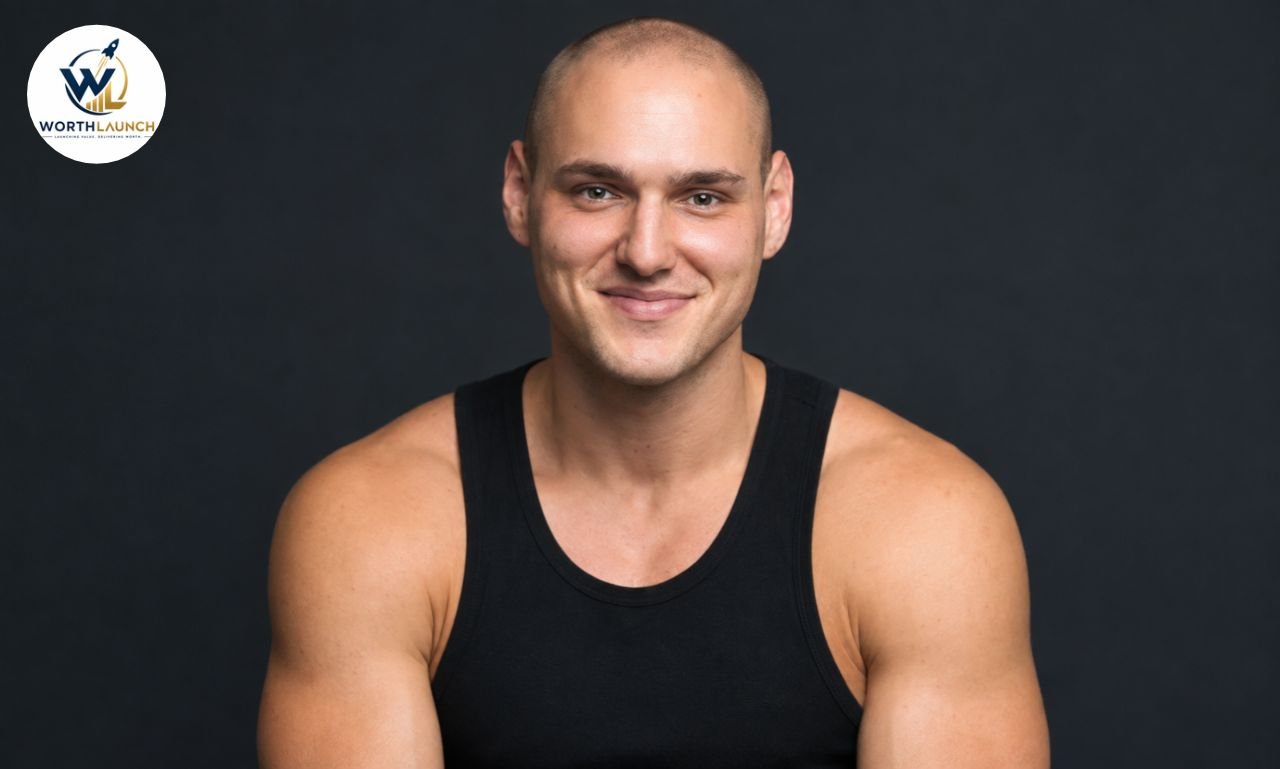 Leo Skepi in a black tank top posing for a professional studio portrait against a dark background.