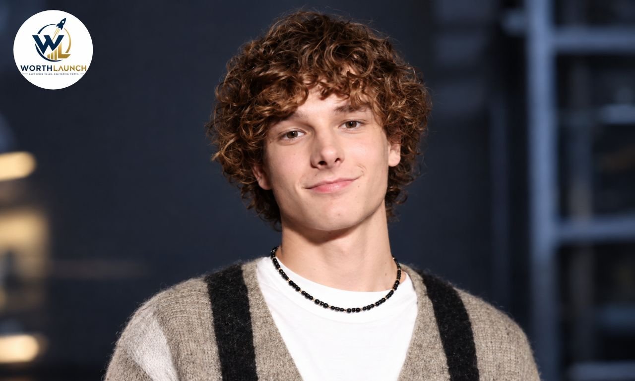 Mason Thames portrait with curly brown hair wearing a beige cardigan and white shirt.