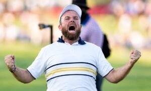 Shane Lowry celebrating on the golf course with his fists raised in victory.