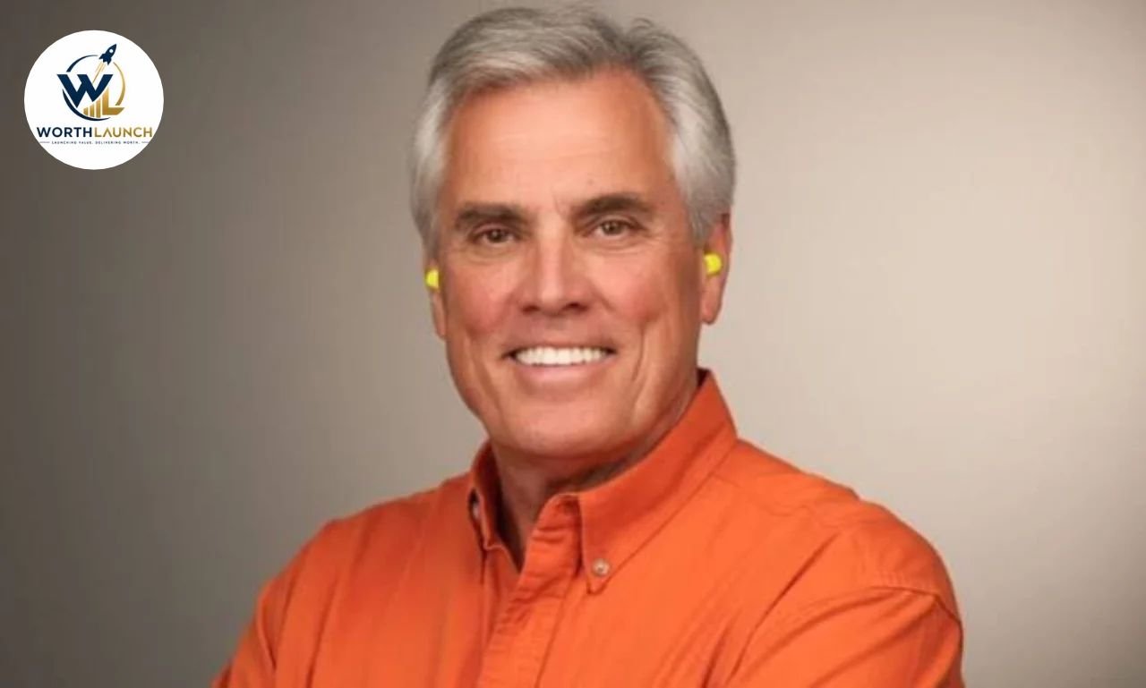 Verne Martell wearing an orange button-down shirt and yellow earplugs in a professional portrait.